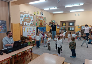 Dzieci tańczą w rytm muzyki granej przez pana rytmika.